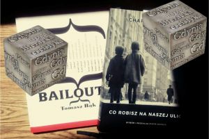 w lewym dolnym rogu zdjęcie: na drewnianym blacie leżą dwie książki, widoczne tytuły: Bailout i Co robisz na naszej ulicy; na pierwszym planie częściowo na tle książek dwa sześciany z napisami Gdynia